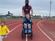 Instructional Assistant Iain Culp walks with Teag Gaboury,  while Uriel Rivera Cruz races alongside them. Photo by Jacalyn Vigus