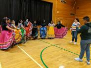 Jazelle Terrell (white striped sweater) works with senior Ime Guzman to prepare the MEChA dancers for a photo.