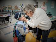 Hubbard resident Jan Jurchen, aka Grandma J, gently cups second-grader Kaleb Braden’s young cheeks in her hands. 