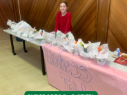 Student standing behind table that reads kindness