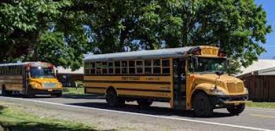 Two yellow school buses driving on Grim Road