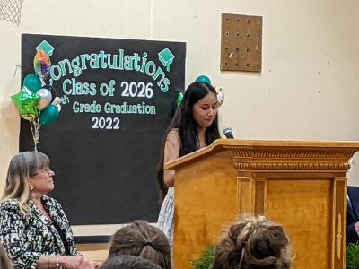 High School Principal De Ann Jenness listens as eighth-grader Yaharit Cisneros Gonzalez delivers her speech. 