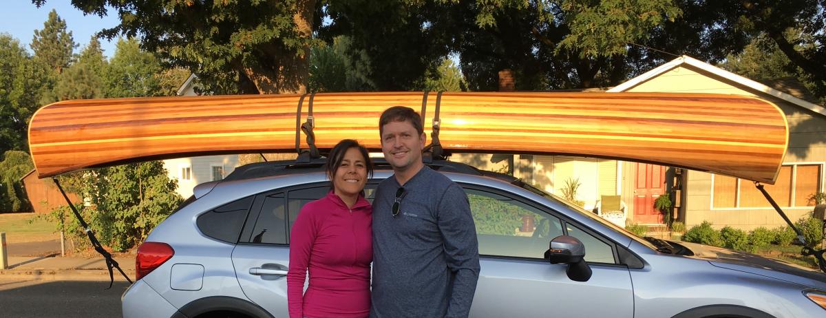Richard Goddard and Wendy Véliz stand by their car with a canoe on the top of it. Photo courtesy of Goddard