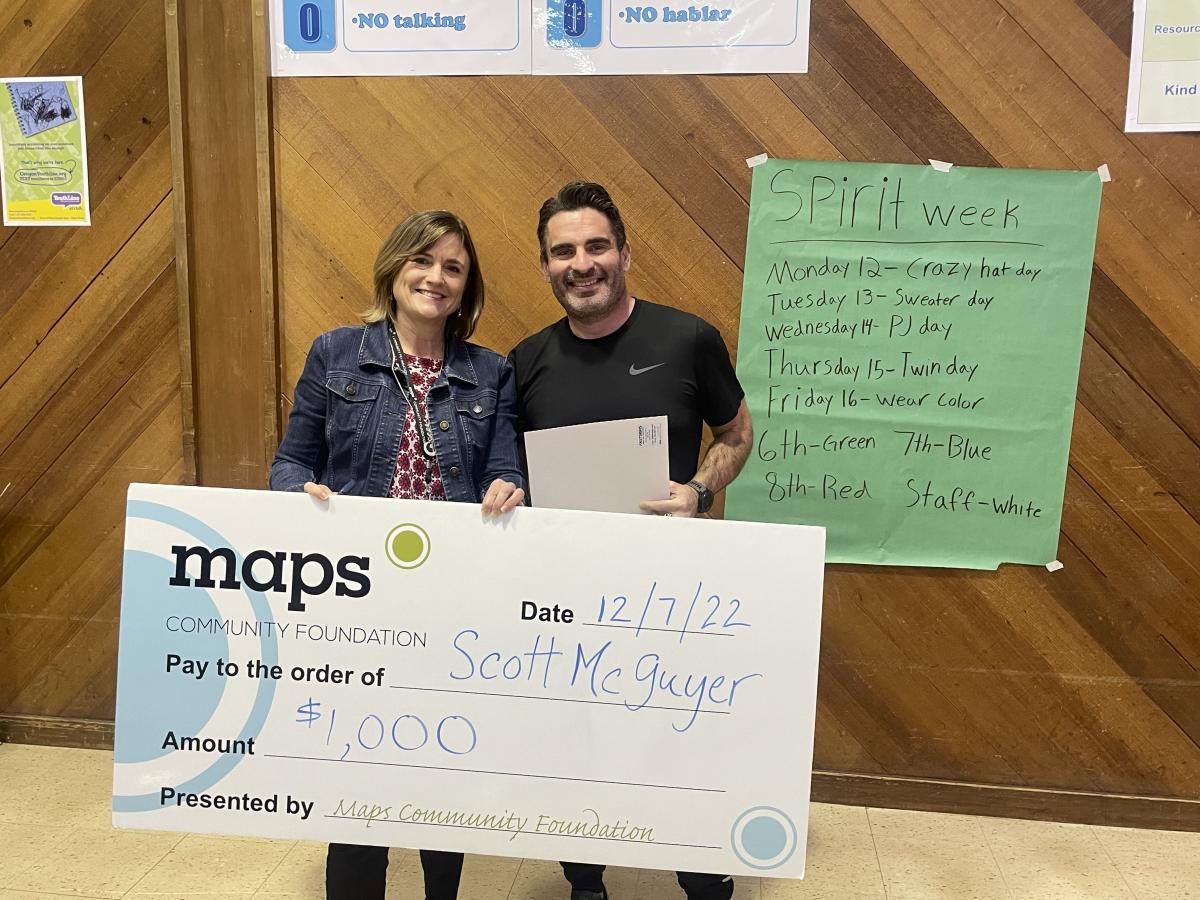 Map Community Foundation Executive Director Kim Hanson, left, hands Middle School Teacher Scott McGuyer a donation for $1,000.