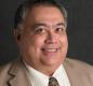 Bill Graupp's professional headshot in which he is a wearing a tan jacket and brown tie