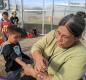 Volunteer Glenda Creekmore paints Axel Camacho Flores’s arm as Kelvin Gerdes walks past and Denali Bosco tends to the goats.