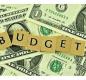 Budget pic with scrabble tiles on top of cash
