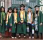 Graduates wearing caps and gowns beam for the photo